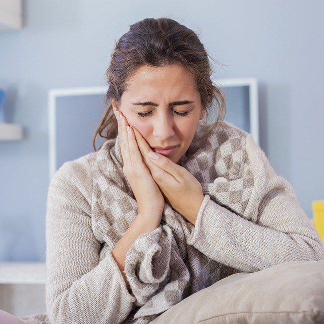 Woman in need of emergency dentistry holding cheek in pain