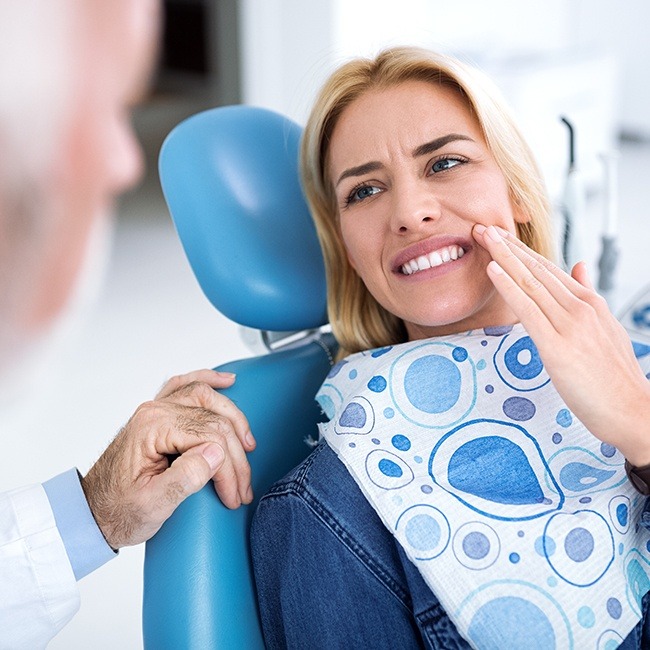 Woman with lost dental crown holding cheek