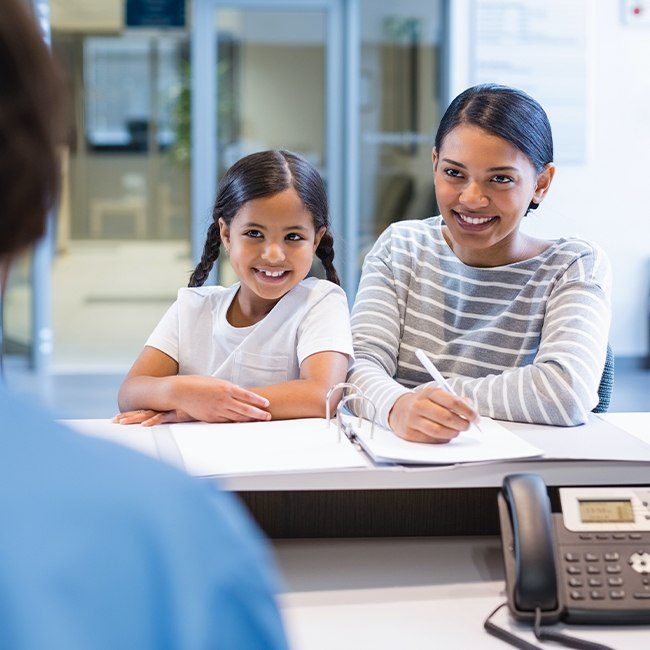 Mother and daughter checking in at dental office reception desk