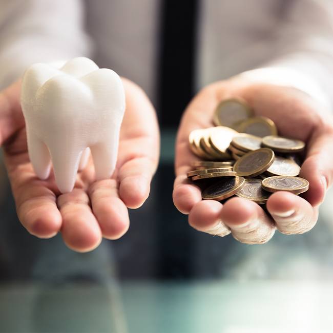 Hand with a tooth and hand with coins