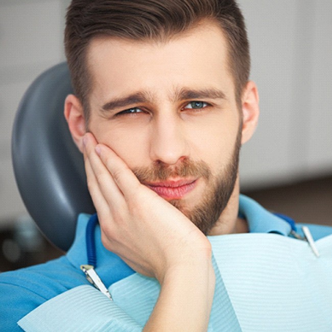 man experiencing the symptoms of dental implant failure