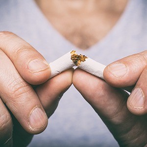 Closeup of patient with dental implants in Los Angeles breaking cigarette 