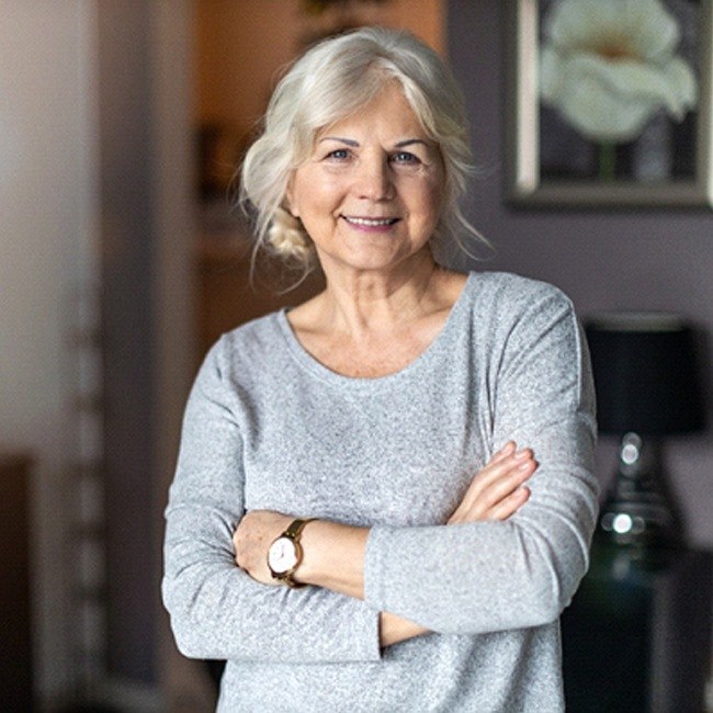 Woman with implant dentures standing with arms folded