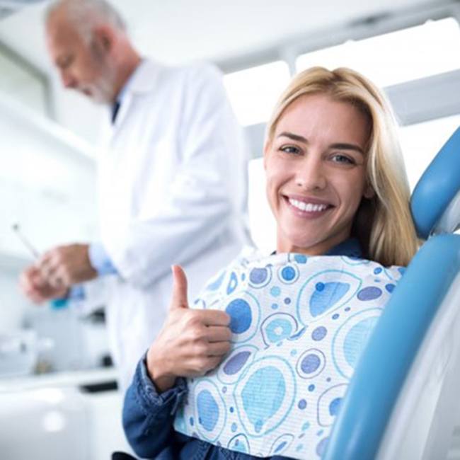 woman giving a thumbs up while visiting her implant dentist in Log Angeles 