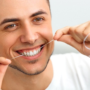 man gently flossing his teeth for oral hygiene