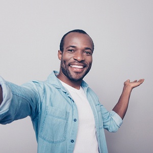 man taking a selfie and enjoying life after replacement teeth are attached