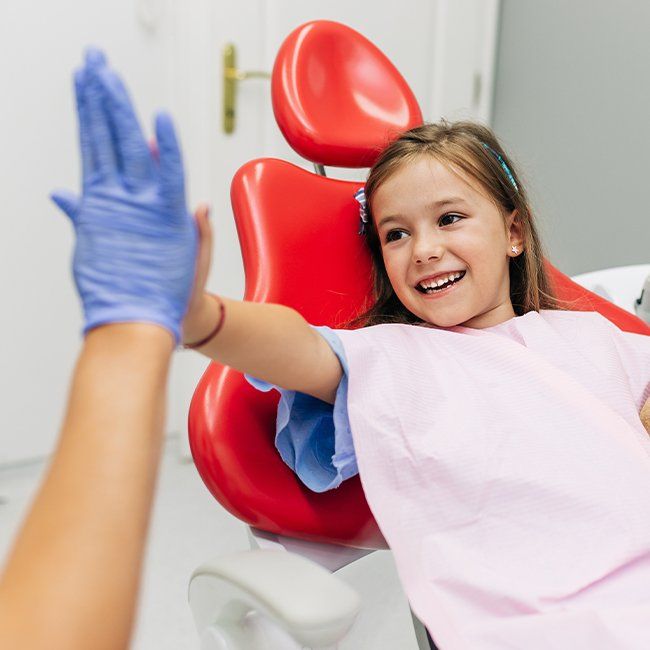 Little girl giving dentist a high five during children's dentistry visit