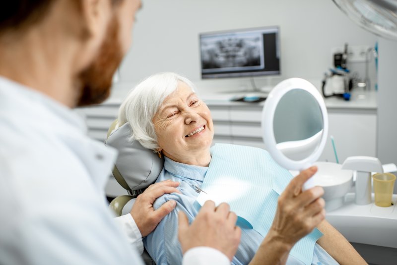 Senior woman smiling at reflection at dentist's office
