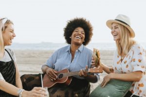 three friends sitting on the beach and hanging out together