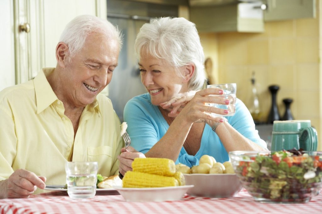 Older couple with dental implants enjoying summer foods.