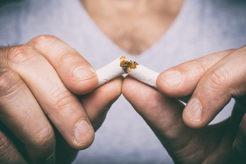 man quitting smoking by breaking cigarette in half